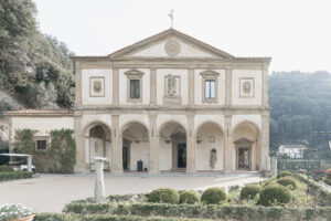 A front view of Villa San Michele, a historical building in Florence, Italy, featuring a Renaissance facade attributed to Michelangelo, with arched entrances and a serene garden in the foreground.