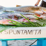 A collection of the catch of the day displayed on palm leaves over a blue and white boat at Four Seasons PUNTA MITA