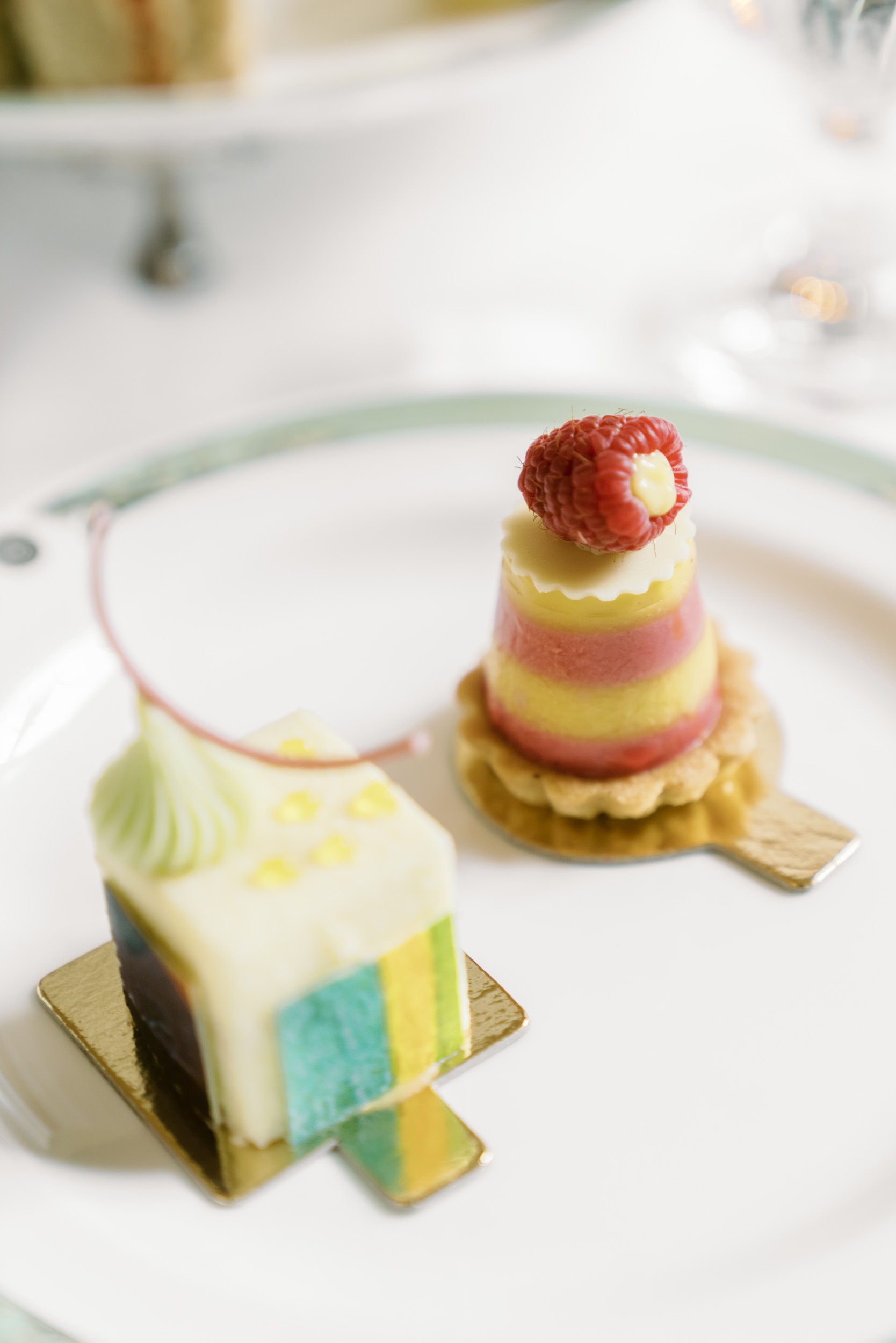 Colorful high tea pastries inspired by art, topped with raspberry and intricate designs.