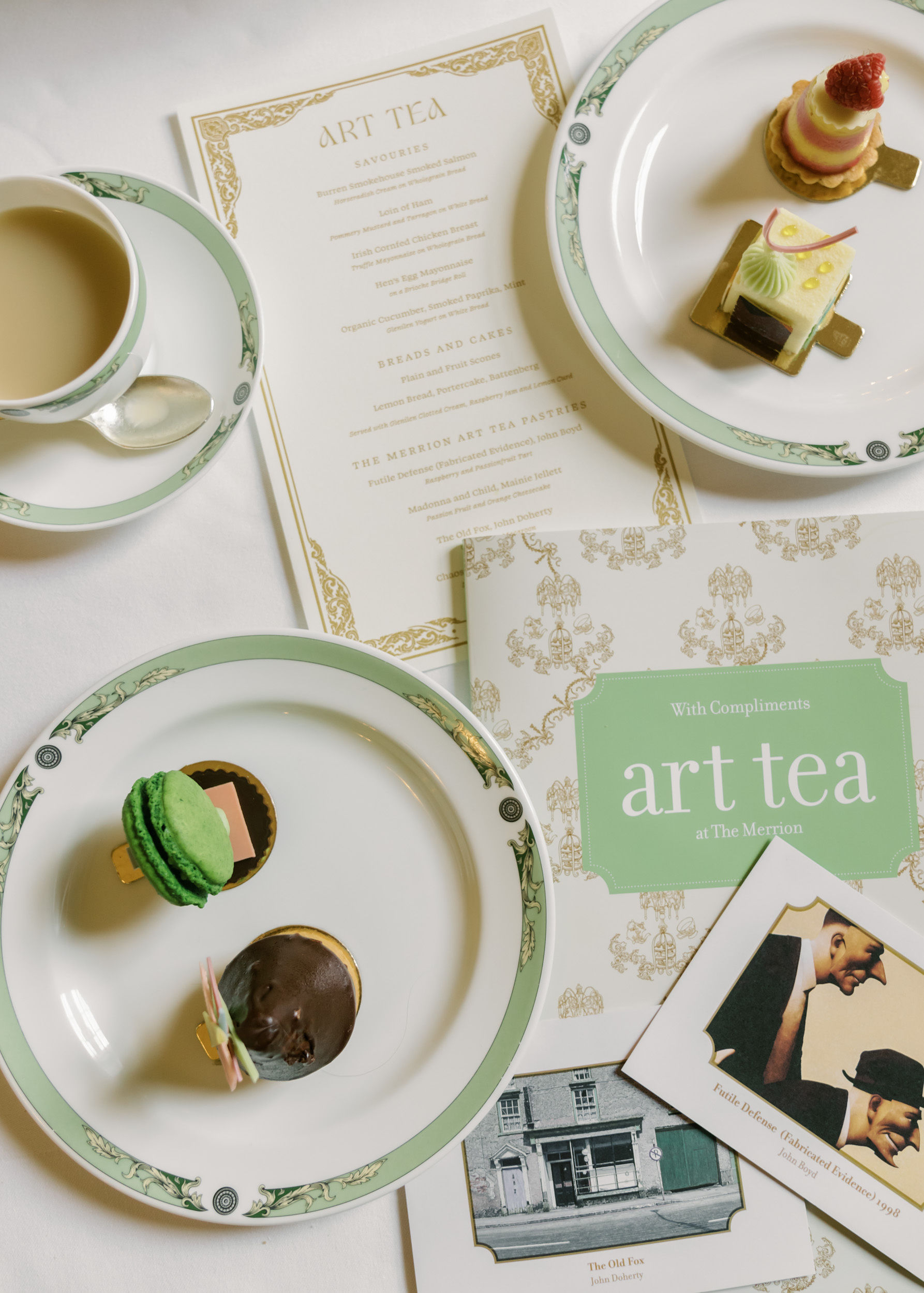 Flat lay of art tea menu, pastries, macarons, and a cup of tea at The Merrion.